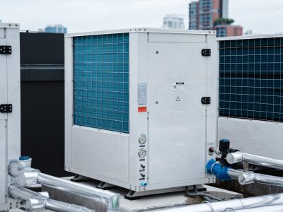 Air conditioner compressor installed on the roof of a building, along with industrial air conditioning units and ventilation systems.
